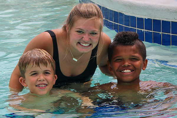 Counselor with two boys in swimming pool