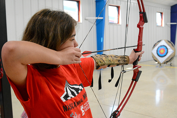 Camper aiming bow at archery center