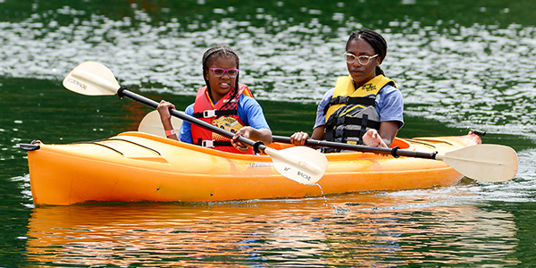 Counselor and girl camper rowing kayak