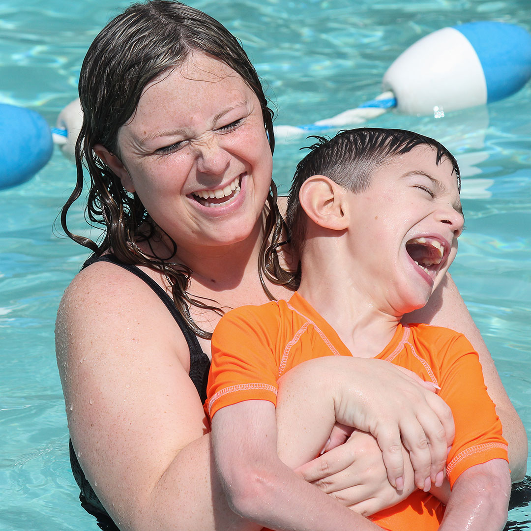 Counselor laughing with boy camper in pool