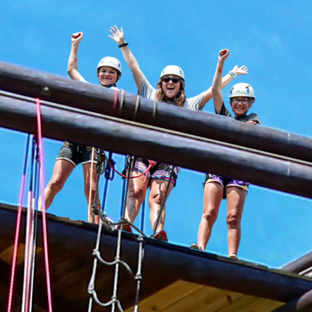 Campers and counselors waving from top of adventure tower