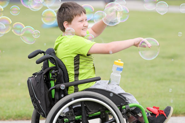 Camper in wheelchair reaching for bubbles