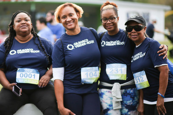 Four women wearing running shirts and bibs smiling