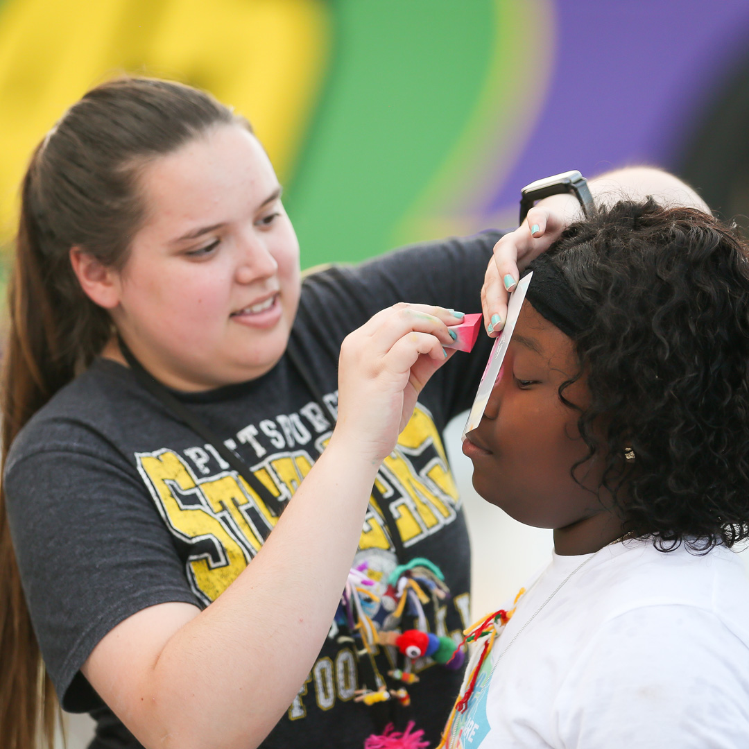 Claire painting a camper's face during NASCARnival.