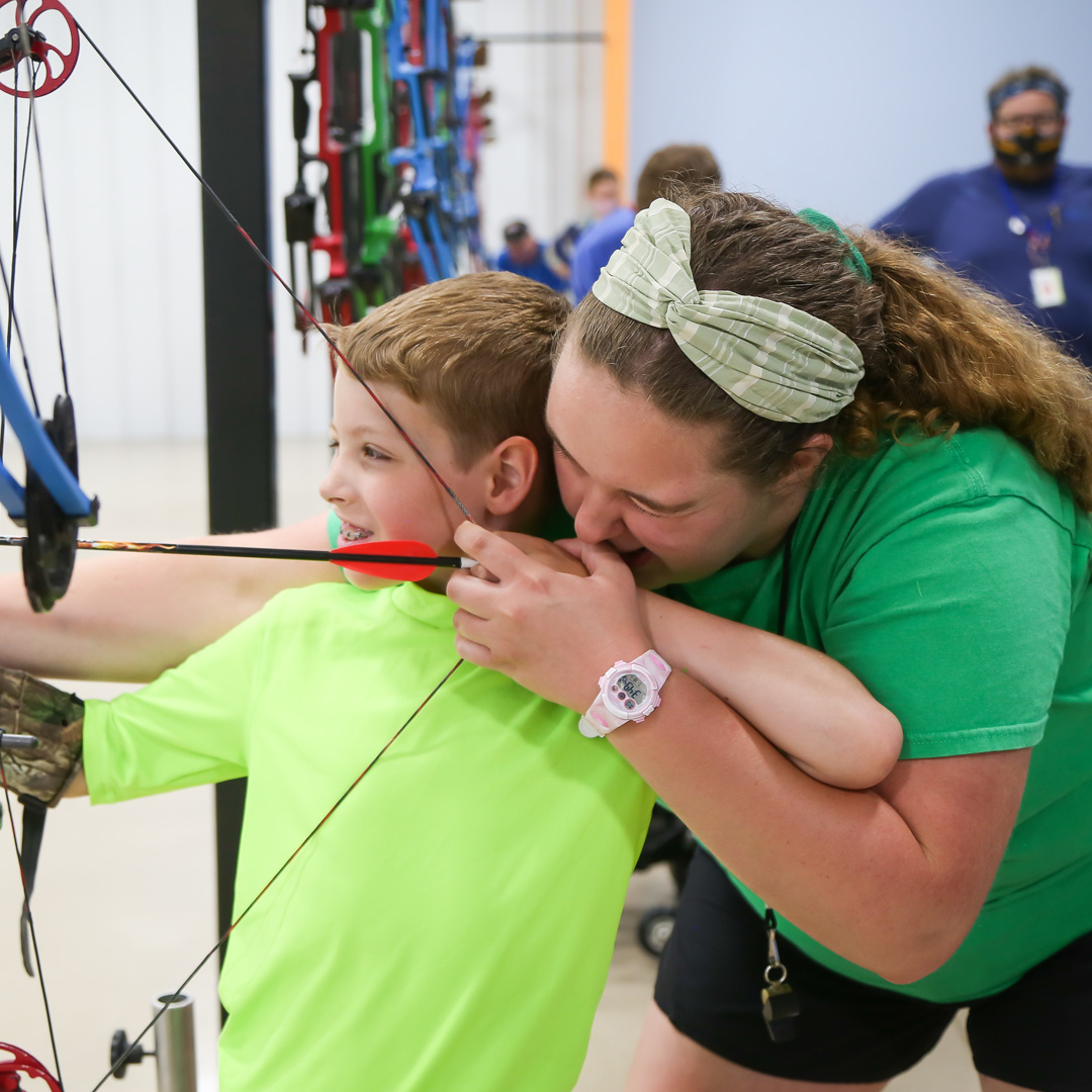 Sarah assisting a camper with archery.