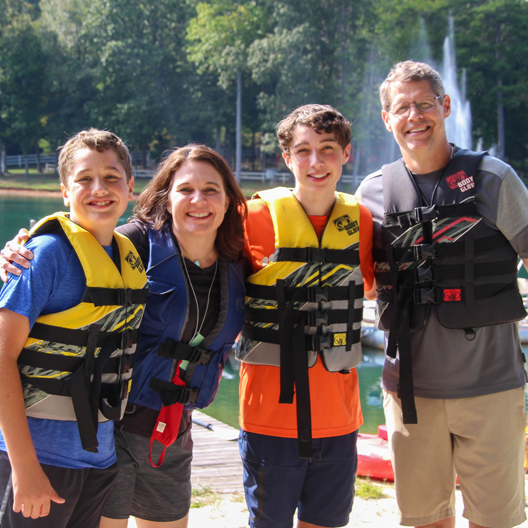 Family in wearing life vests poses in front of the lake