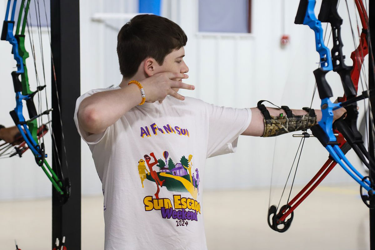 A camper shoots a bow and arrow at the indoor archery range.