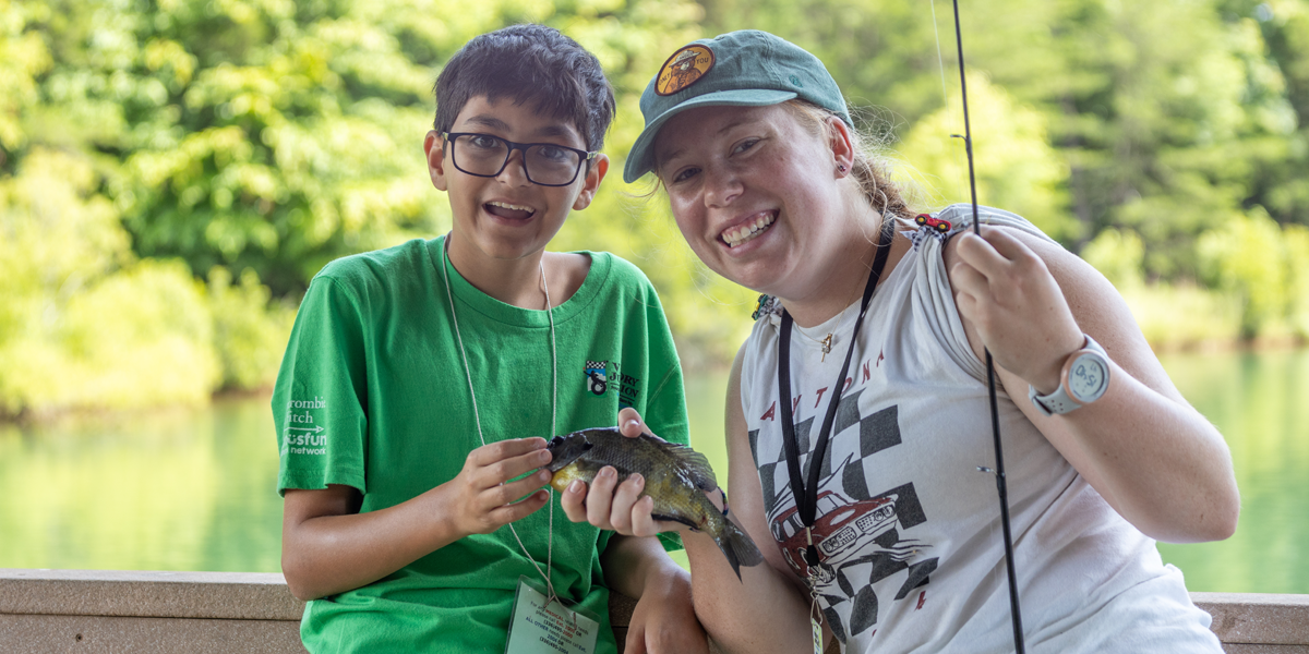 About Image 1 1200x600 Camper and counselor with fish.