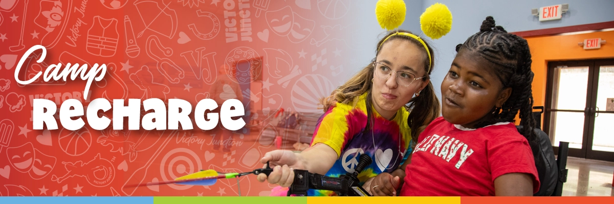 A Victory Junction volunteer helps a camper use a bow and arrow during an archery activity at Camp Recharge.