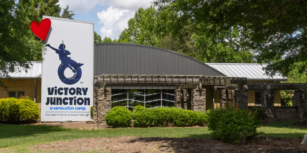Exterior view of the Victory Junction Spiritual Center surrounded by trees and landscaped grounds.