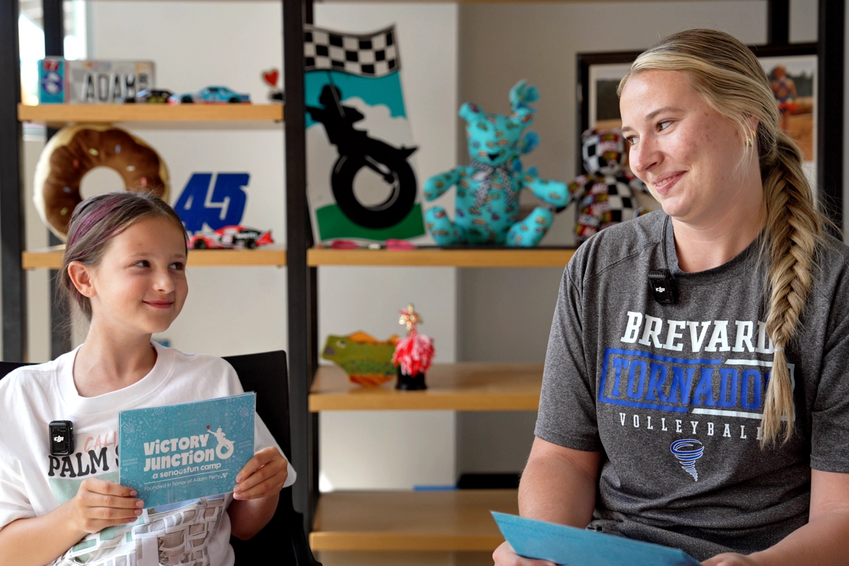 Camper and counselor smiling at each other while holding interview cards during a conversation at Victory Junction.