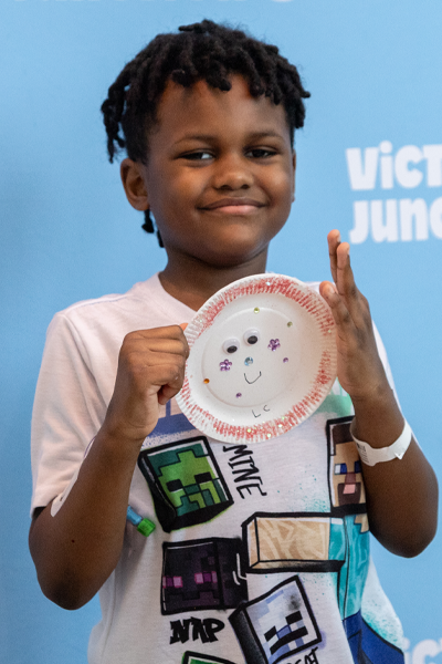 Victory Junction OUTREACH Image 5 A smiling boy proudly displays a paper plate craft he created during a Victory Junction OUTREACH activity.